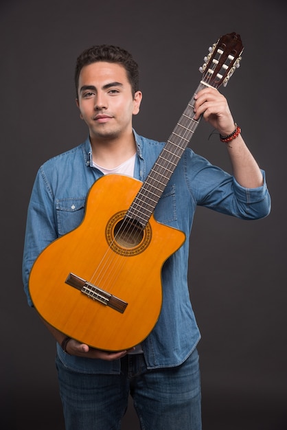 Jeune musicien tenant la guitare sur fond noir