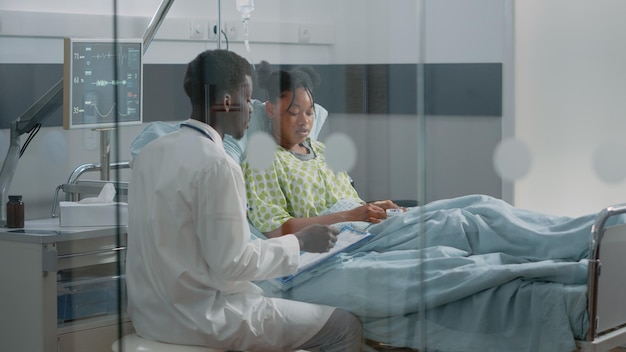 Jeune patient recevant une consultation médicale d'un médecin en salle d'hôpital. un médecin spécialiste parle à une femme malade au lit d'un traitement sur ordonnance et de soins de santé pour guérir la maladie.