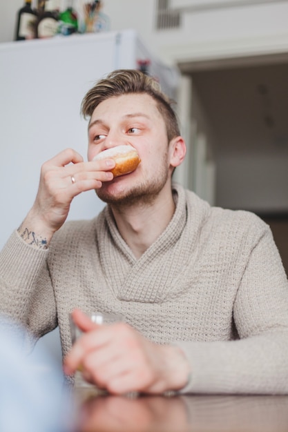 Un jeune père mordant un beignet savoureux