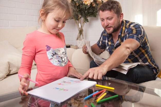 Un jeune père qui pointe le dessin de sa fille