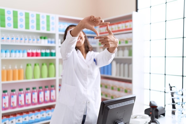 Photo gratuite jeune pharmacienne afro-américaine souriante confiante faisant un geste photo avec les mains à la pharmacie