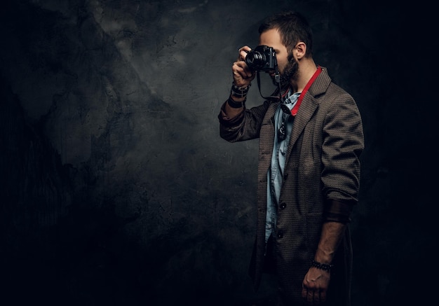 Photo gratuite un jeune photographe concentré prend une photo sur le fond grunge sombre.
