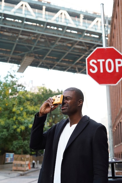 Jeune photographe masculin élégant utilisant l'appareil photo tout en explorant la ville