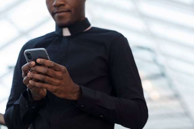 Jeune prêtre mâle à l'aide de smartphone