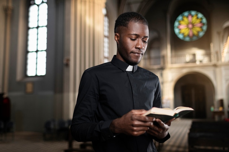 Photo gratuit jeune prêtre masculin tenant le livre saint dans l'église