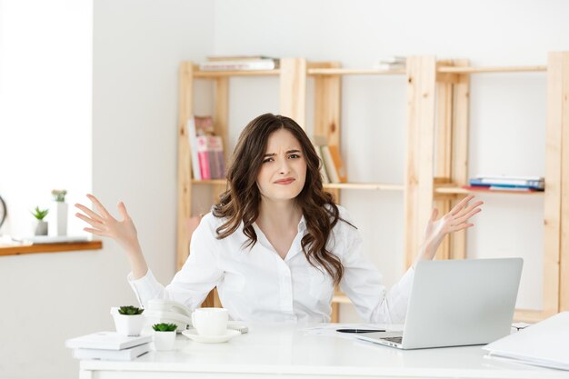 Jeune propriétaire d'une petite entreprise à la recherche d'un ordinateur portable et ressent des maux de tête avec ses pertes d'entreprise Idée de concept de pertes d'entreprise