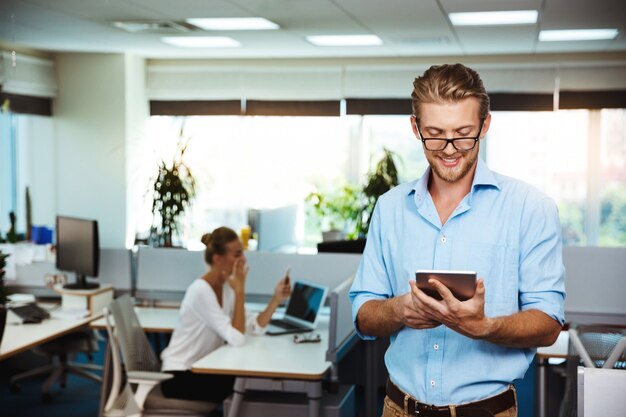 Jeune, réussi, homme affaires, sourire, regarder, tablette, bureau