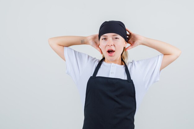 Jeune serveuse bâillant et étirant les bras en uniforme et vue de face de tablier.