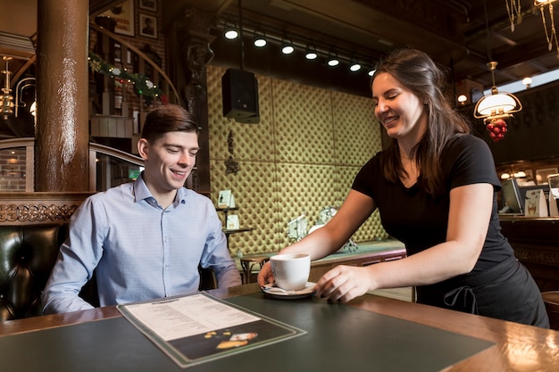 Jeune serveuse servant du café au client