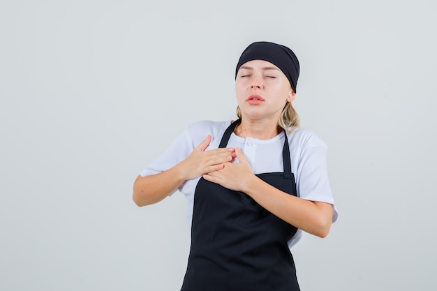 Jeune serveuse en uniforme et tablier souffrant de douleurs thoraciques