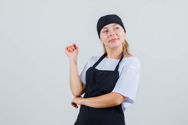 Jeune serveuse à la voiture en uniforme et tablier et à la recherche d'espoir