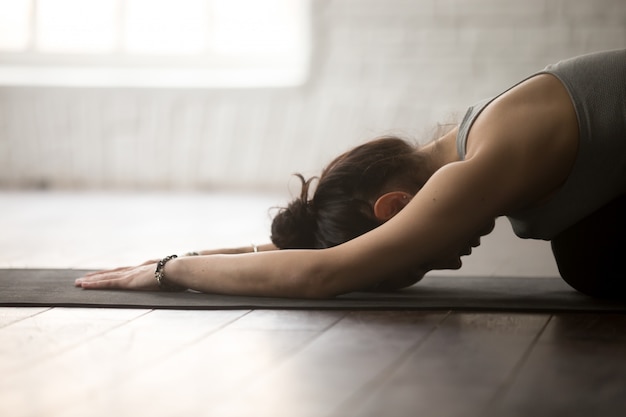 Jeune, sportive, pose, Balasana, studio loft blanc, gros plan