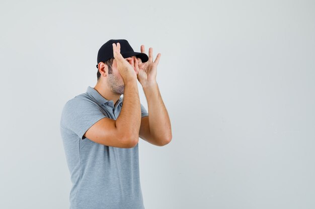 Jeune technicien montrant le geste de lunettes en uniforme gris et à la recherche concentrée.