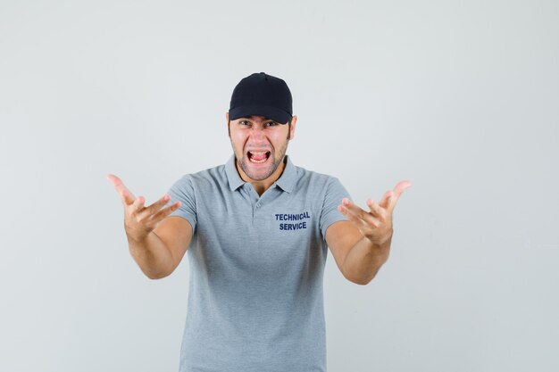 Jeune technicien en uniforme gris gardant les mains de manière agressive.