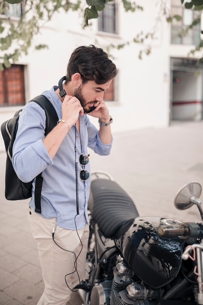 Jeune touriste masculin debout près de sa moto