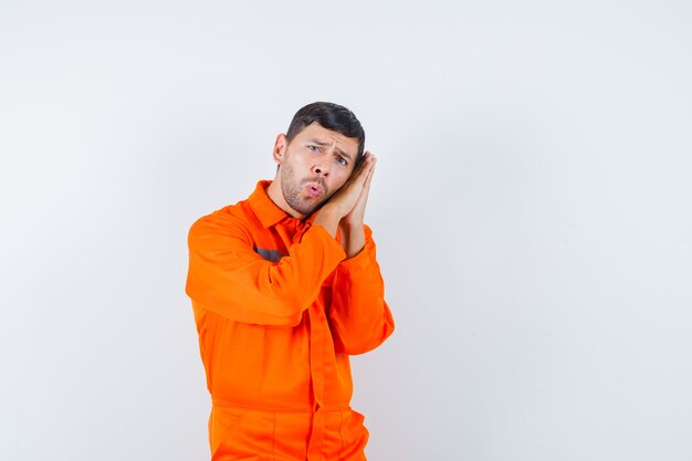 Jeune travailleur appuyé sur les paumes comme oreiller en uniforme.