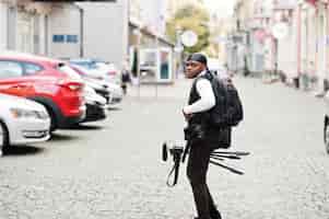 Photo gratuite jeune vidéaste afro-américain professionnel tenant une caméra professionnelle avec un équipement professionnel de trépied caméraman afro portant du duraq noir faisant des vidéos