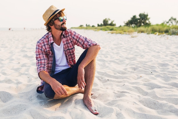 Jeune voyageur assis sur du sable blanc