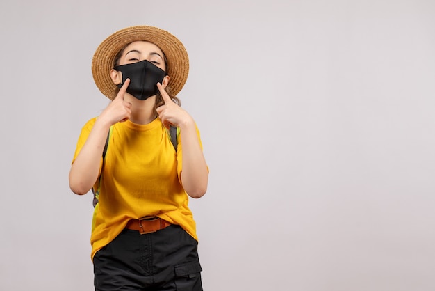 Jeune voyageuse vue de face avec sac à dos pointant sur son masque