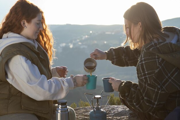 Jeunes amies buvant du thé chaud dans les montagnes