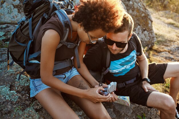 Jeunes amis assis sur rocher dans le canyon, regardant la boussole