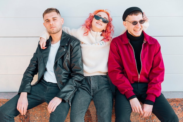 Photo gratuite jeunes amis embrassant et assis sur un banc dans la rue