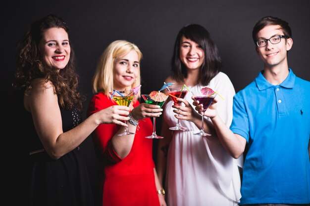 Jeunes amis posant avec des cocktails