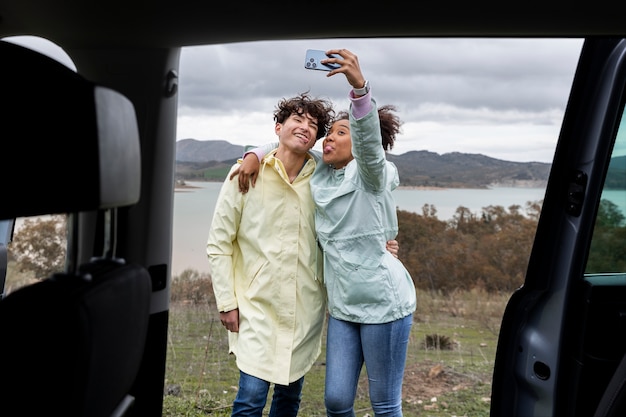 Photo gratuite jeunes amis prenant un selfie lors d'un voyage en voiture familier