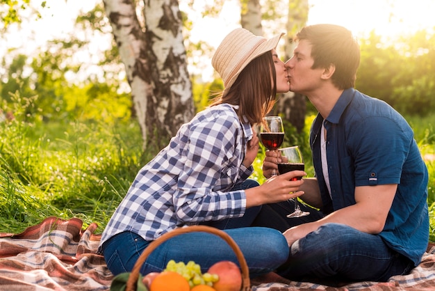 Jeunes amoureux assis sur un plaid et s&#39;embrasser