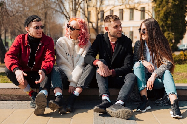 Jeunes assis sur un trottoir et se parlant