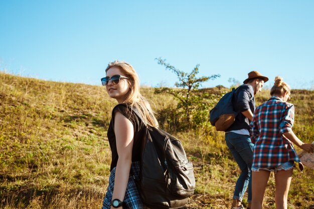 Jeunes beaux amis avec des sacs à dos en remontant la colline