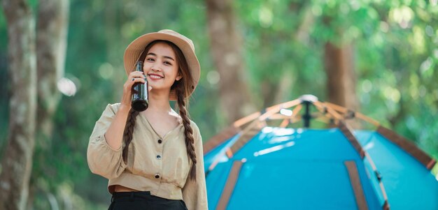 Jeunes belles femmes asiatiques et amis voyageurs se détendant devant la tente de camping Ils aiment parler et boire de la bière avec plaisir et heureux ensemble