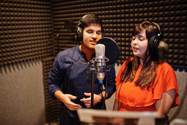 Jeunes chanteurs asiatiques en duo avec microphone enregistrant une chanson dans un studio de musique d'enregistrement