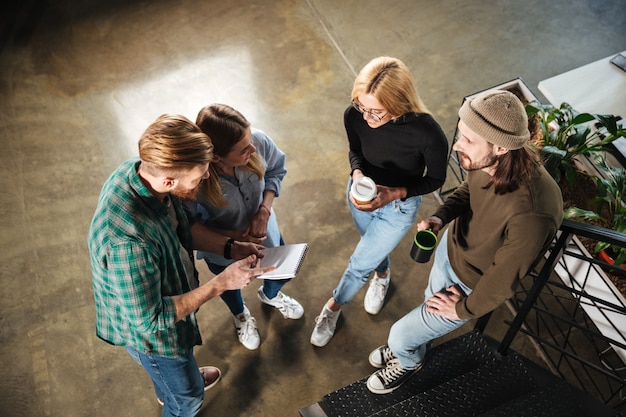 Jeunes collègues de bureau parler entre eux tenant un ordinateur portable