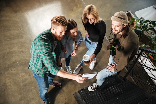 Jeunes collègues de bureau parler entre eux tenant un ordinateur portable