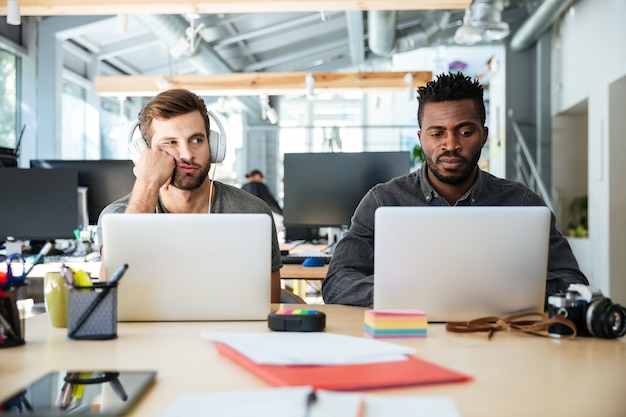 Photo gratuite jeunes collègues confus assis dans le coworking de bureau