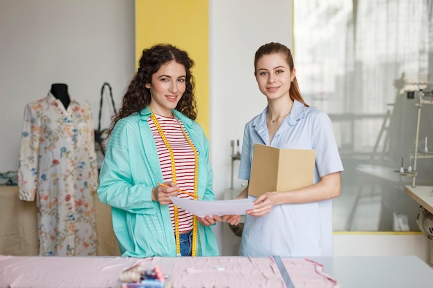 Jeunes designers souriants regardant joyeusement à huis clos travaillant ensemble dans un atelier de couture moderne