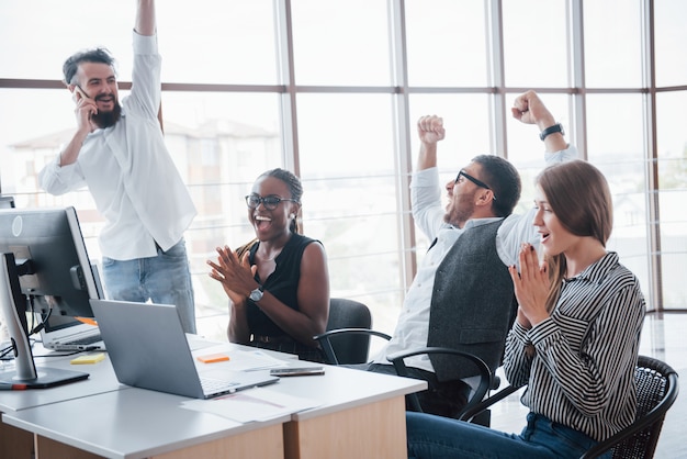 Les jeunes employés assis au bureau à la table et à l'aide d'un ordinateur portable