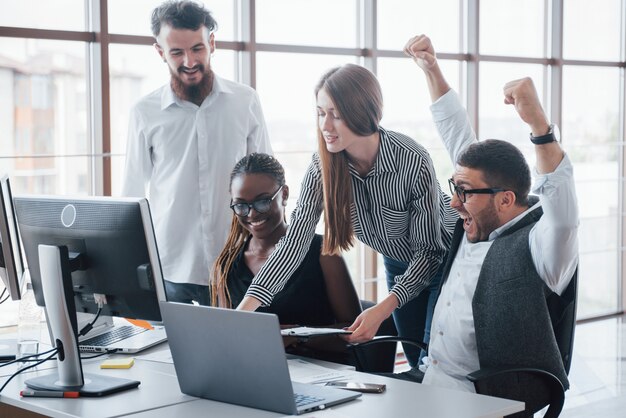 Les jeunes employés assis au bureau à la table et à l'aide d'un ordinateur portable