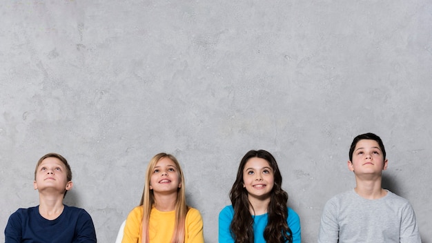 Photo gratuite jeunes enfants de faible angle assis sur des chaises