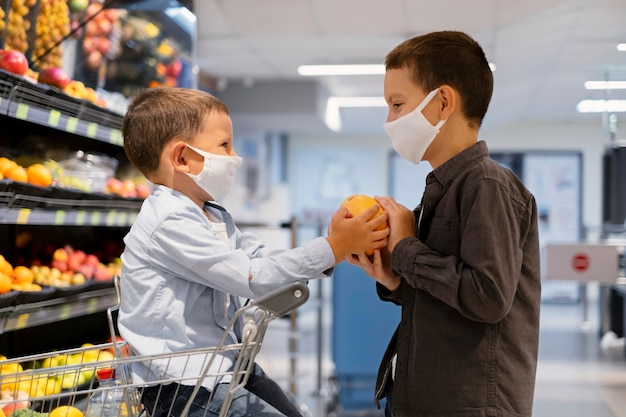 Photo gratuite jeunes enfants faisant du shopping avec des masques