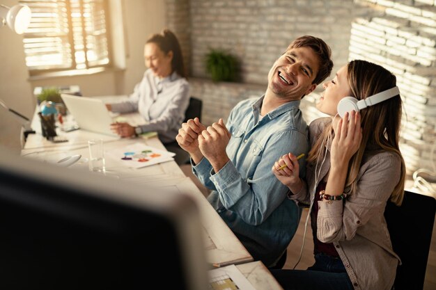 Jeunes entrepreneurs joyeux s'amusant tout en travaillant ensemble au bureau