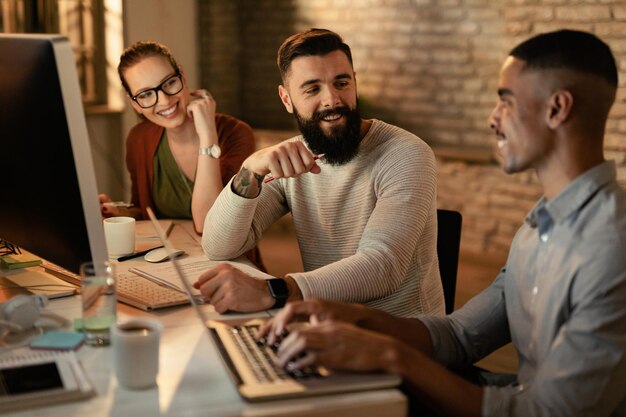 Jeunes entrepreneurs travaillant tard et communiquant au bureau L'accent est mis sur l'homme à la barbe