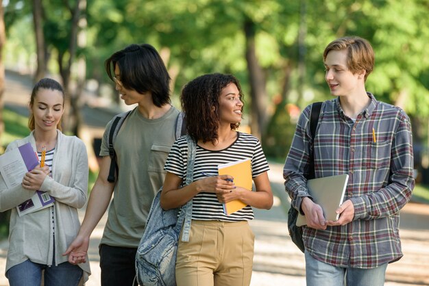 Jeunes étudiants heureux marchant tout en parlant. En regardant de côté.