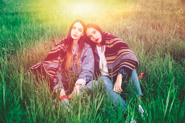 Jeunes femmes assis dans le champ au soleil avec couverture en bandes