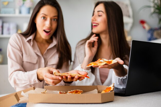 Photo gratuite jeunes femmes ayant une pizza après le travail