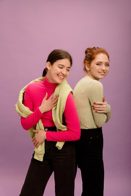 Jeunes femmes caucasiennes souriantes en vêtements décontractés se serrant dans leurs bras sur fond violet Mode de vie de loisirs et concept de beauté