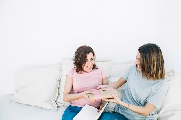 Jeunes femmes donnant présents à la femme à la maison