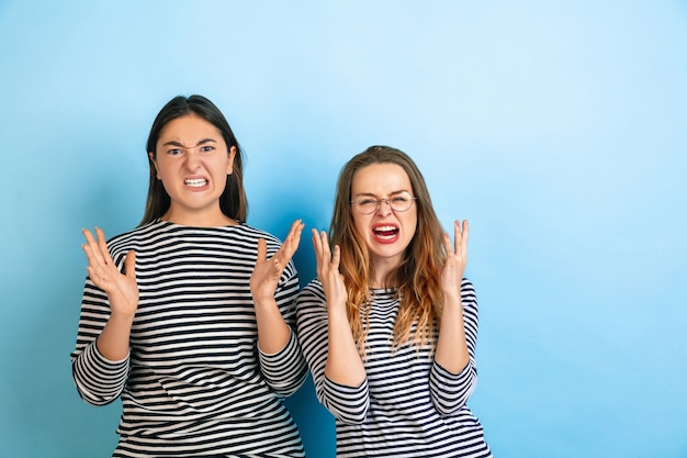 Jeunes femmes émotionnelles isolées sur un mur de studio bleu dégradé