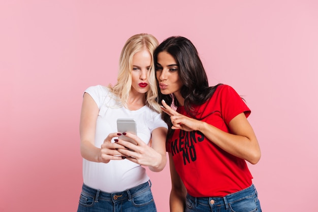 Jeunes femmes faisant selfie et grimaçant isolé
